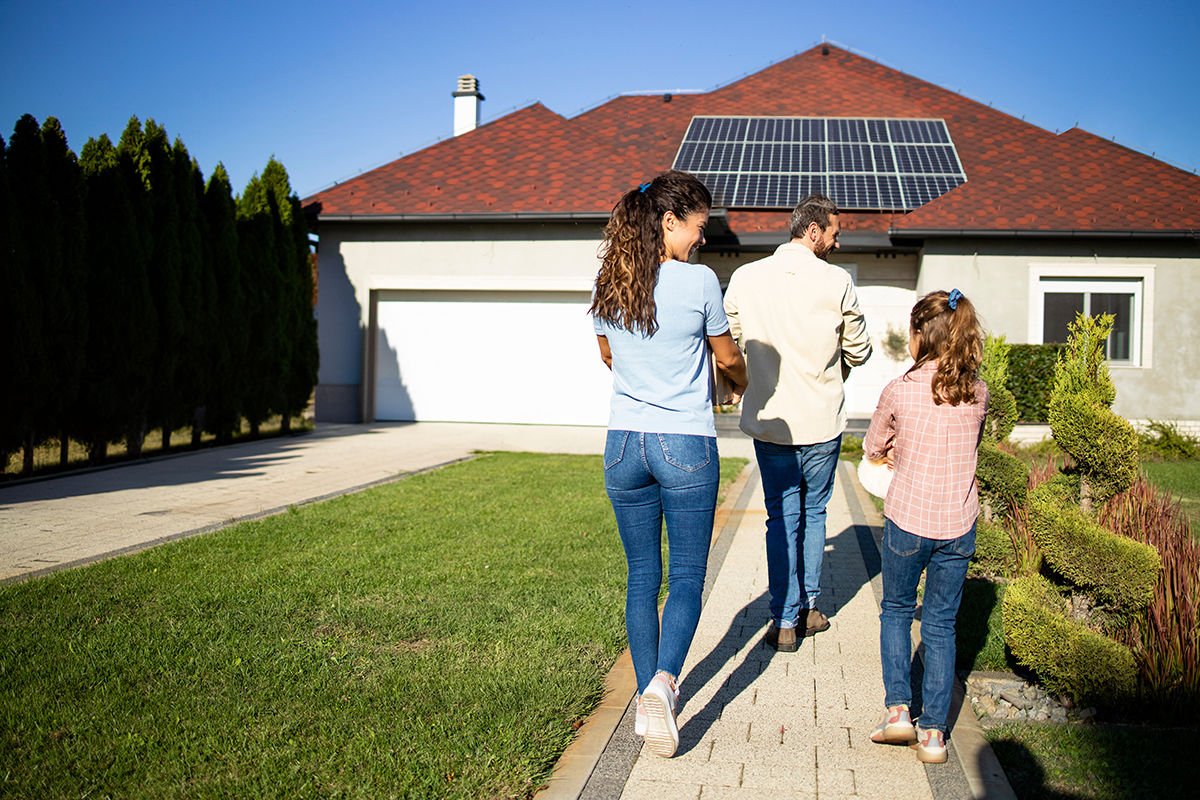 Happy family just bought a new house with solar panels on roof and moving in