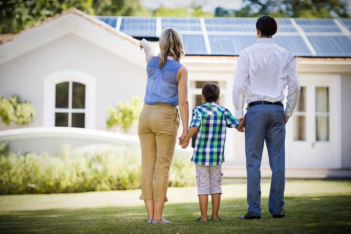 back of family looking at country home with solar on roof on sunny day