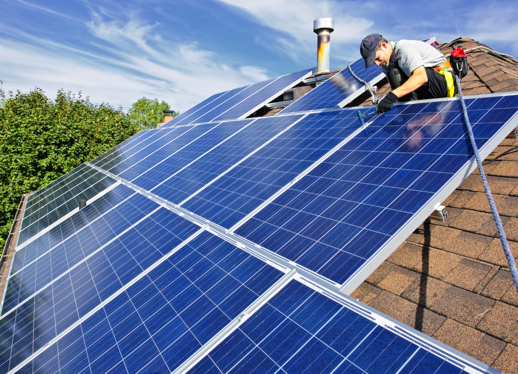 man installing solar panels on residential home roof