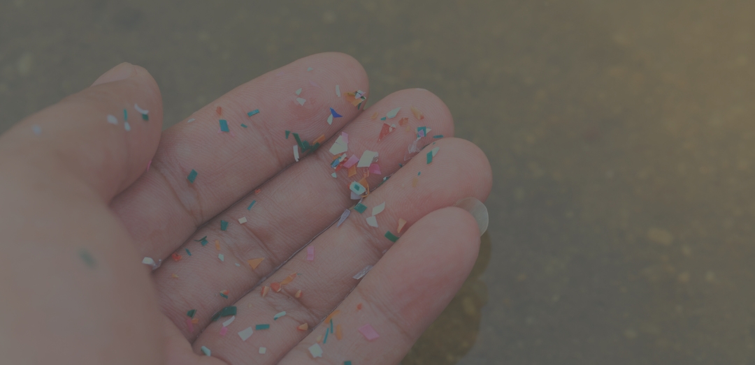 Close-up side shot of hands showing microplastics on the beach. Microplastics are contaminated in the sea and in home products
