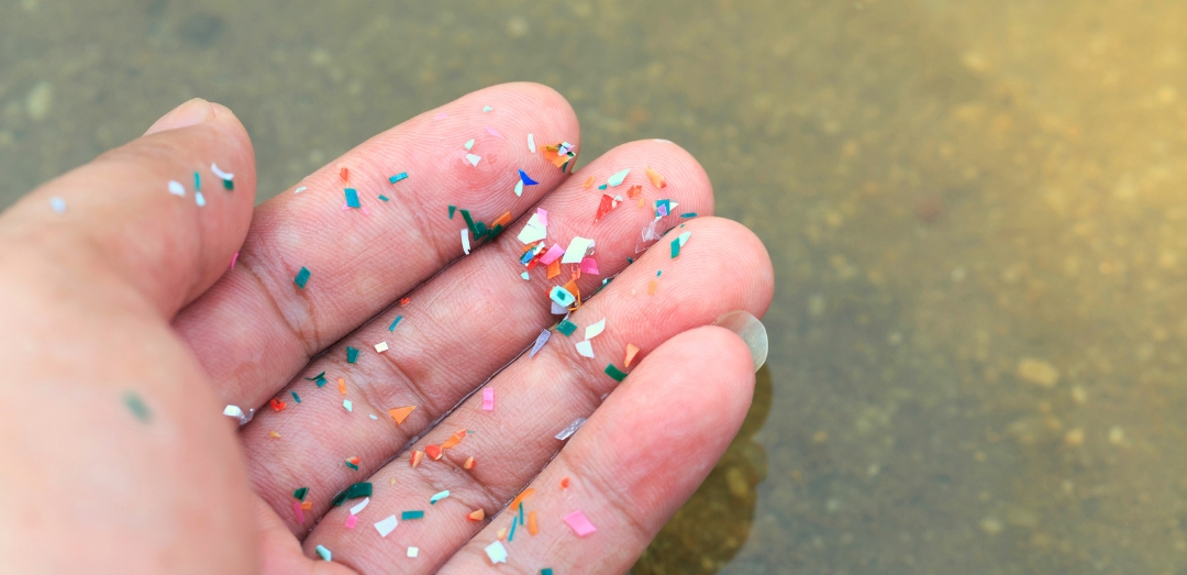 Close-up side shot of hands showing microplastics on the beach. Microplastics are contaminated in the sea and in home products