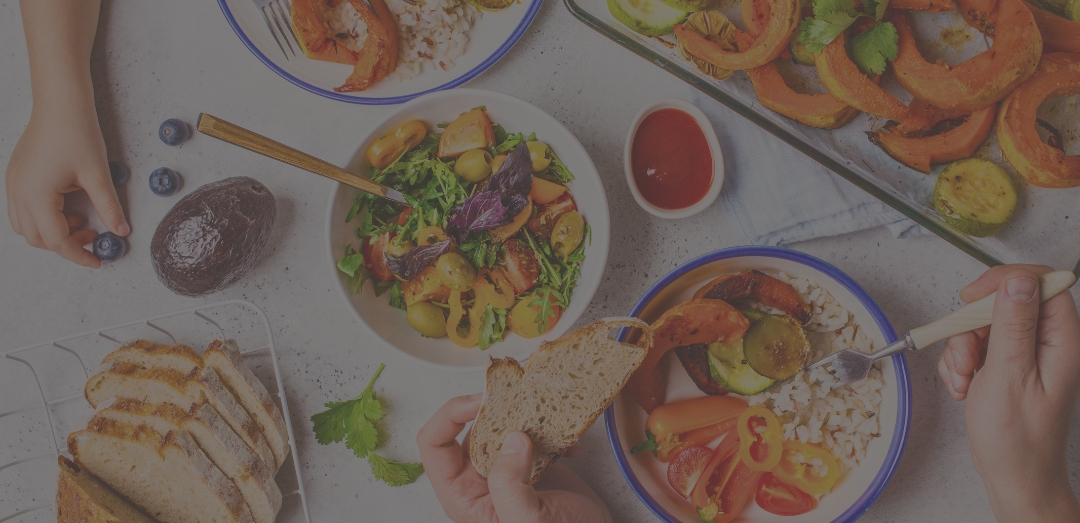 Flat lay of family hands eating healthy food. Vegan lunch table top view. Baked vegetables, fresh salad, berries, bread on a white background.